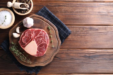 Flat lay composition of raw beef meat and spices on wooden table. Space for text