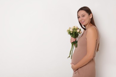Beautiful pregnant woman in beige dress with bouquet of roses on white background, space for text
