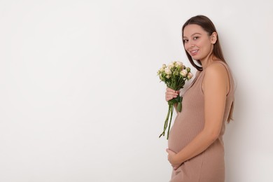 Photo of Beautiful pregnant woman in beige dress with bouquet of roses on white background, space for text