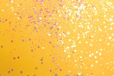 Photo of Shiny bright light violet glitter on yellow background, flat lay
