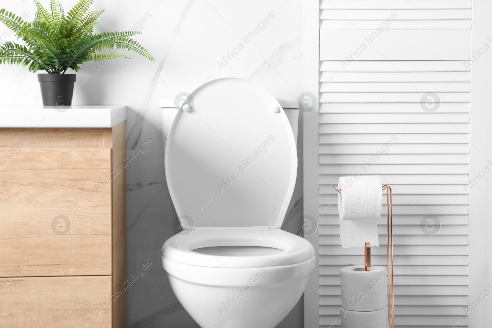 Photo of Holder with paper rolls near toilet bowl in bathroom