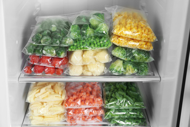 Plastic bags with different frozen vegetables in refrigerator