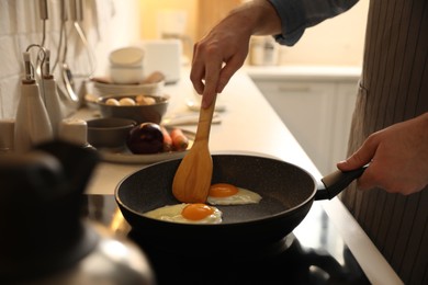 Photo of Man cooking eggs in frying pan, closeup