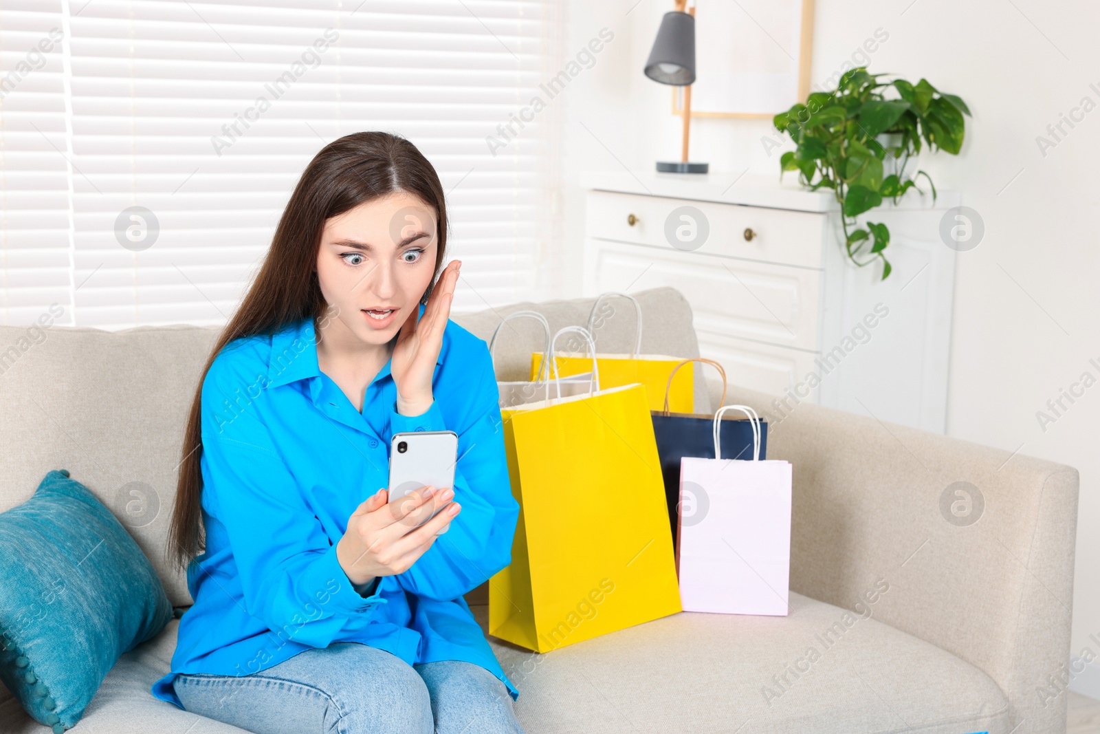 Photo of Special Promotion. Emotional young woman looking at smartphone on sofa indoors