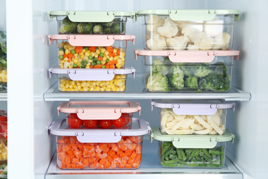 Containers with different frozen vegetables in refrigerator