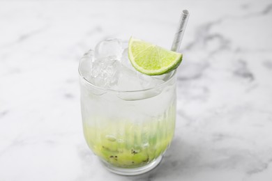 Glass of refreshing drink with kiwi and lime on white marble table, closeup