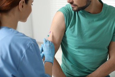 Doctor giving hepatitis vaccine to patient in clinic, closeup