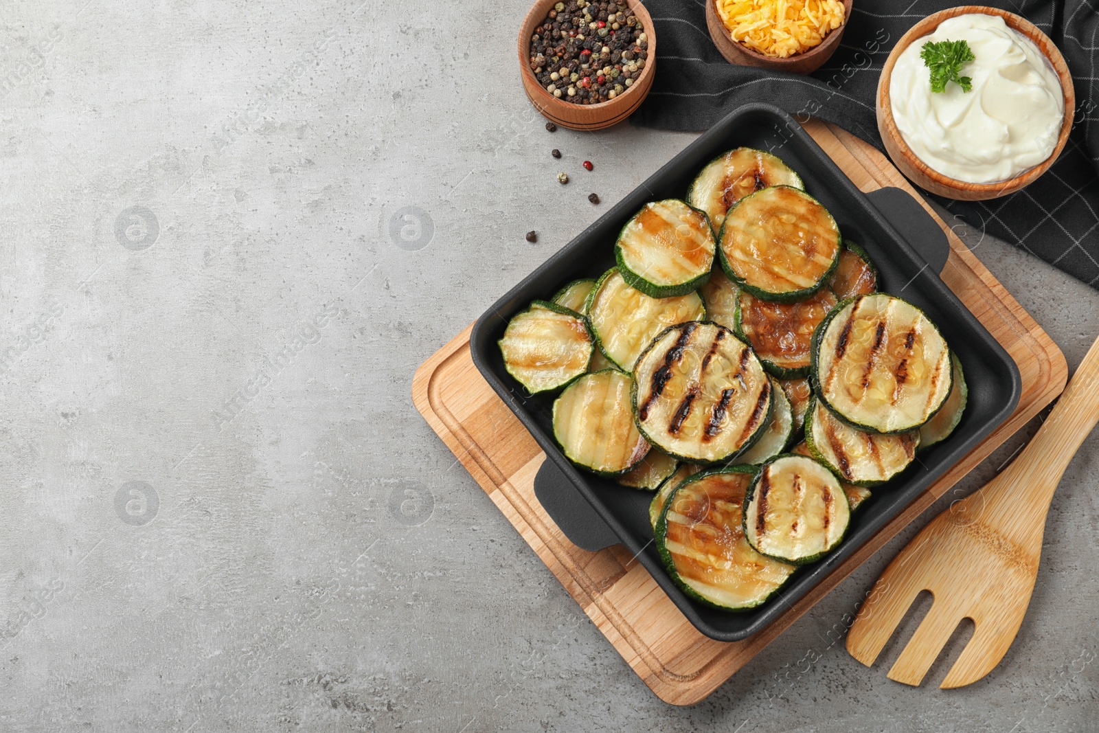 Photo of Flat lay composition with delicious grilled zucchini slices on grey table. Space for text