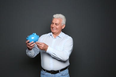 Photo of Mature man with piggy bank on grey background
