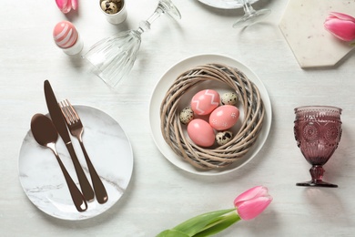 Festive Easter table setting with painted eggs on wooden background, top view