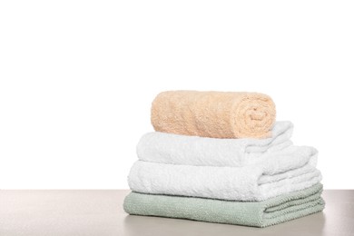 Photo of Soft colorful terry towels on light table against white background, space for text