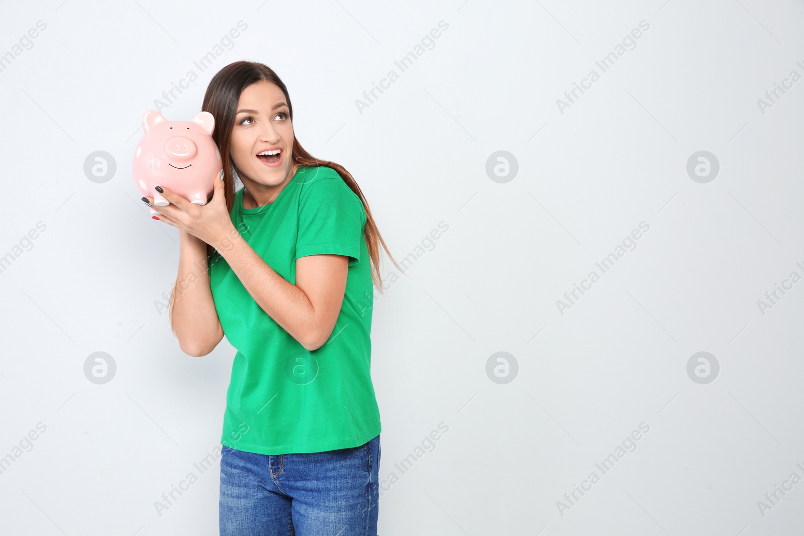 Photo of Young woman with piggy bank on white background. Space for text