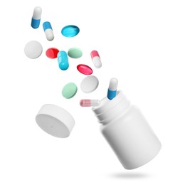 Many different colorful pills falling into bottle on white background