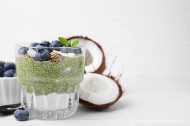 Tasty chia matcha pudding with coconut and blueberries on white table, space for text. Healthy breakfast