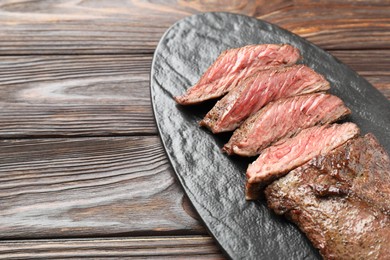 Photo of Pieces of delicious grilled beef meat on wooden table, closeup. Space for text