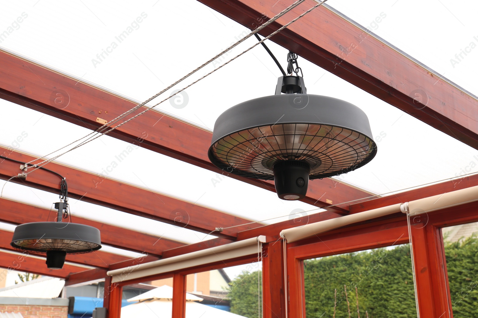 Photo of Stylish hanging infrared heaters on terrace indoors