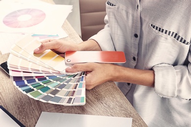 Photo of Woman with color palette samples at table, closeup