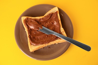 Photo of Tasty toast with chocolate paste and flax seeds on yellow background, top view