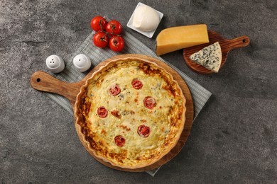 Photo of Delicious homemade cheese quiche and ingredients on gray table, flat lay