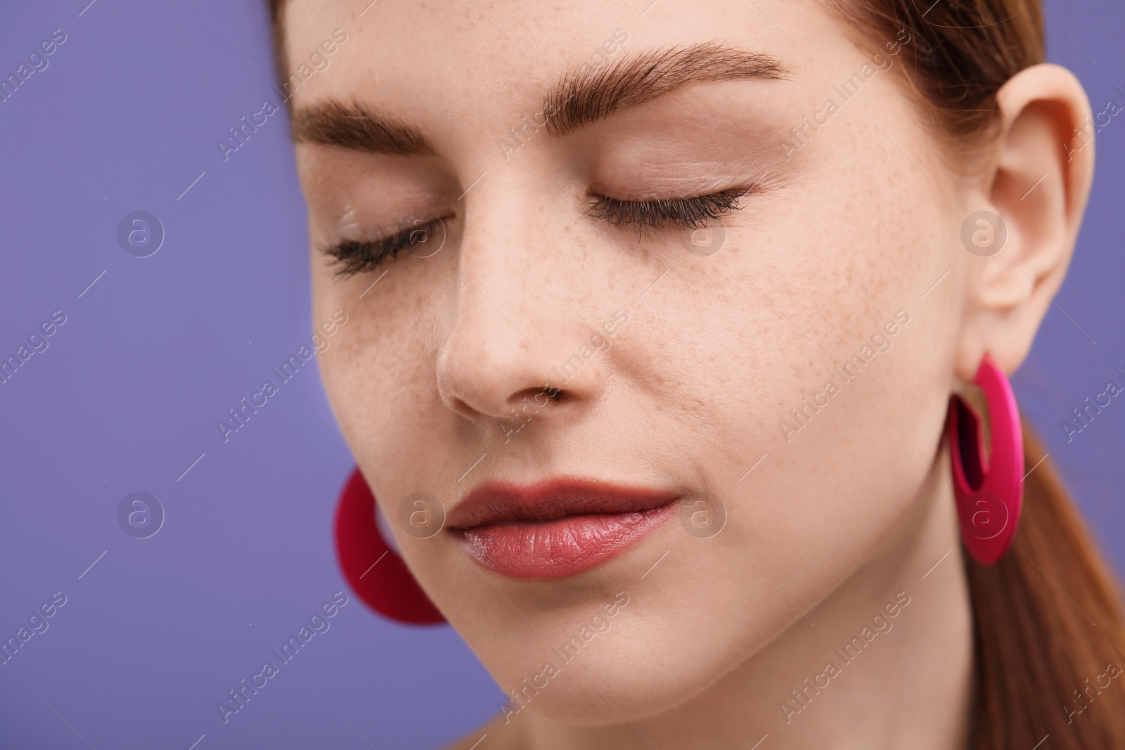 Photo of Portrait of beautiful woman with freckles on purple background, closeup