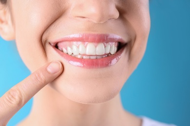 Young woman with healthy teeth and beautiful smile on color background, closeup