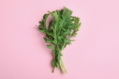 Fresh arugula on light pink background, flat lay