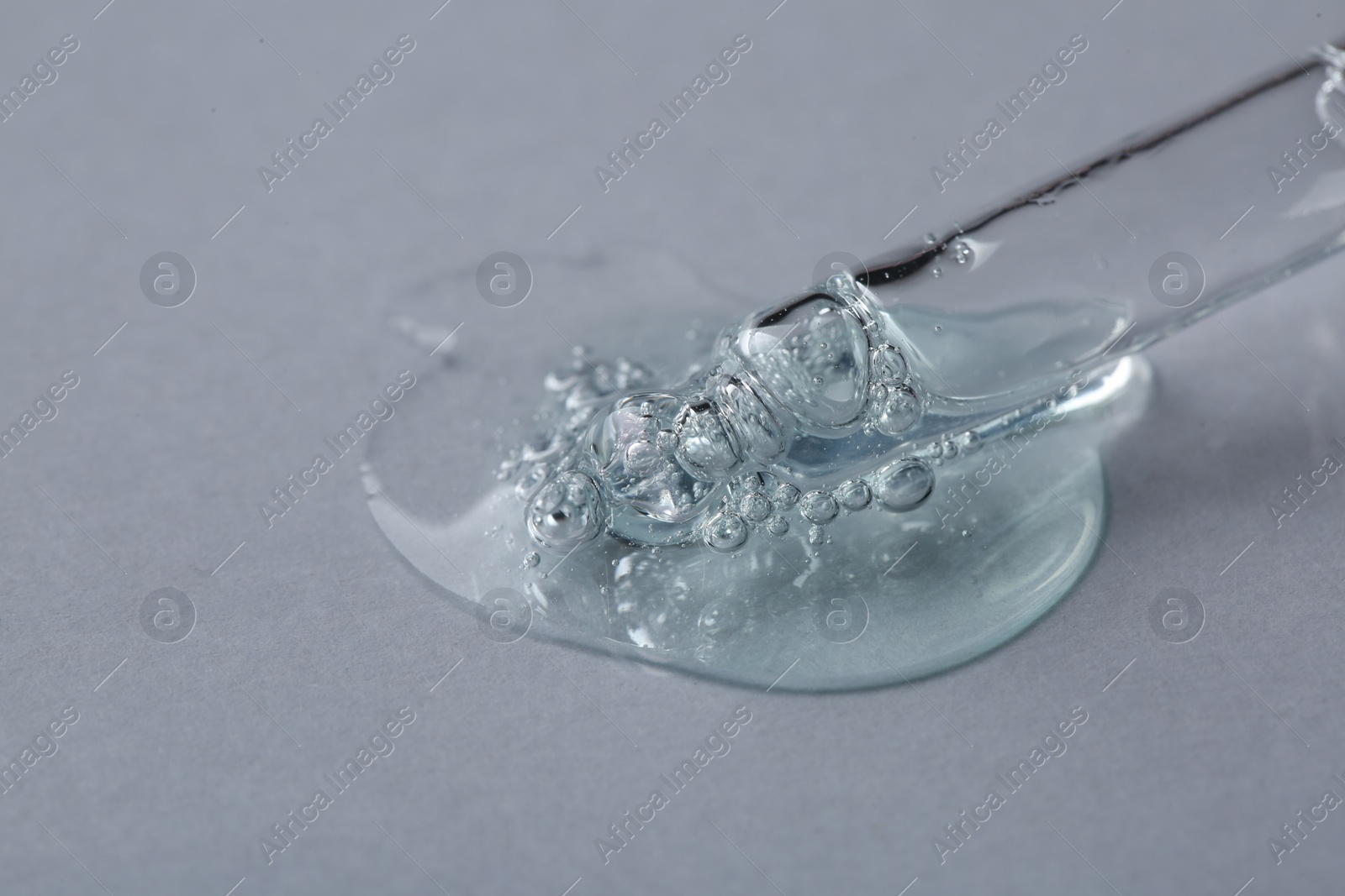 Photo of Pipette with cosmetic serum on white background, macro view