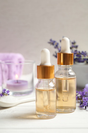 Composition with bottles of essential oil and lavender flowers on white wooden table