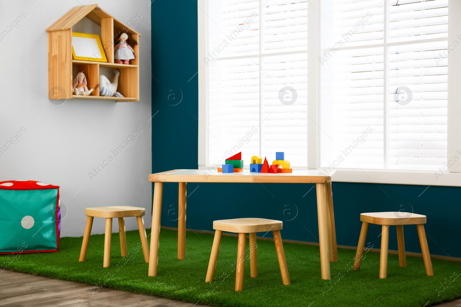 Photo of Stylish playroom interior with wooden table and stools