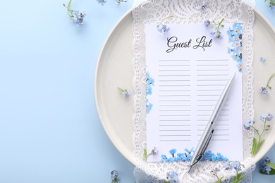 Plate with guest list, pen, lace and flowers on light blue background, flat lay. Space for text