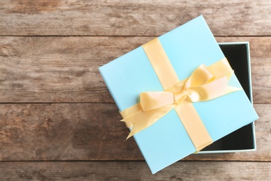 Elegant gift box with bow on wooden background, top view