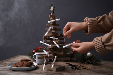 Photo of Woman making advent calendar at wooden table, closeup