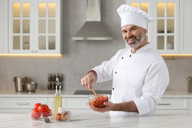 Photo of Professional chef making delicious tomato sauce at white marble table indoors. Space for text