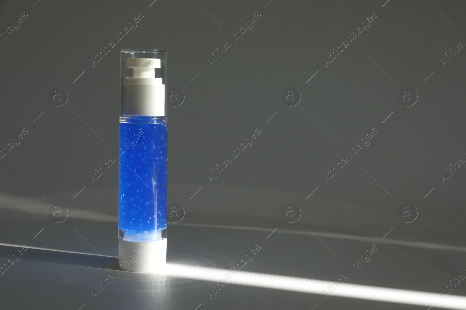 Photo of Bottle of cosmetic product on grey table. Space for text