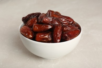 Photo of Sweet dried dates in bowl on light table