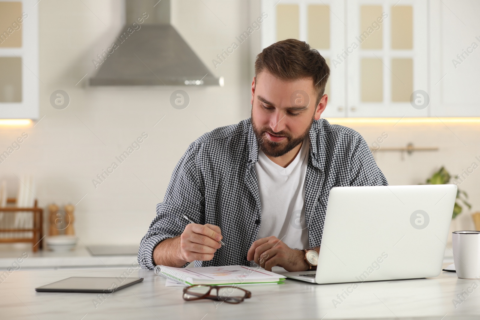 Photo of Young man working with laptop at home