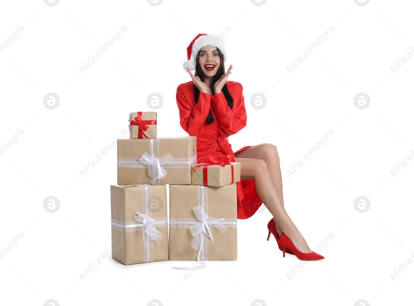 Photo of Excited woman in red dress and Santa hat with Christmas gifts on white background