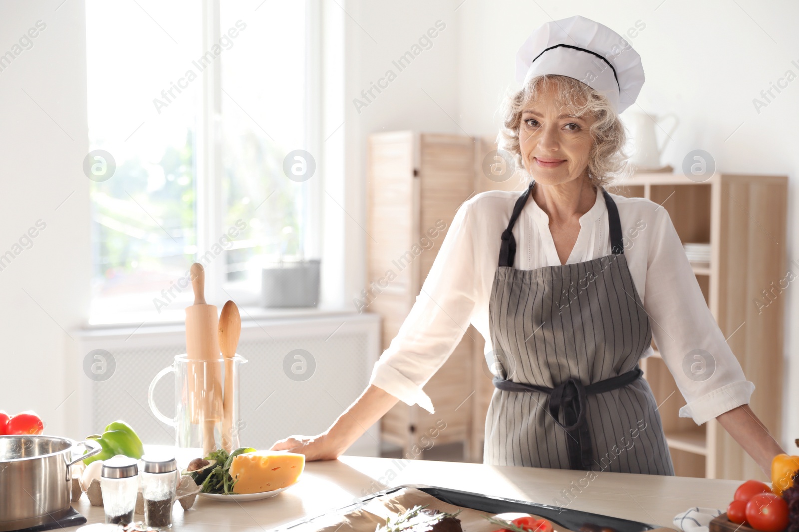 Photo of Professional female chef standing near table in kitchen