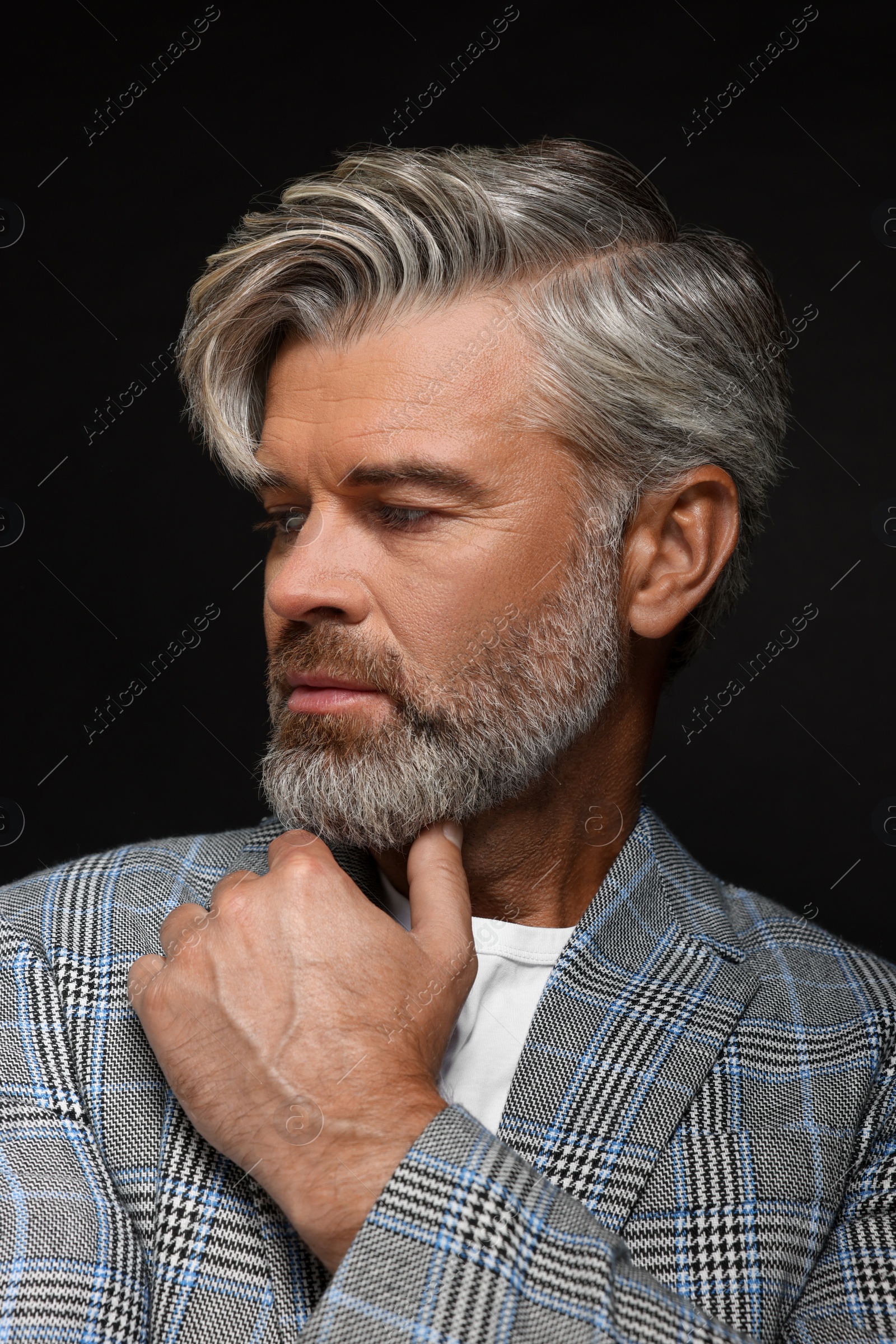 Photo of Portrait of confident man with beautiful hairstyle on black background