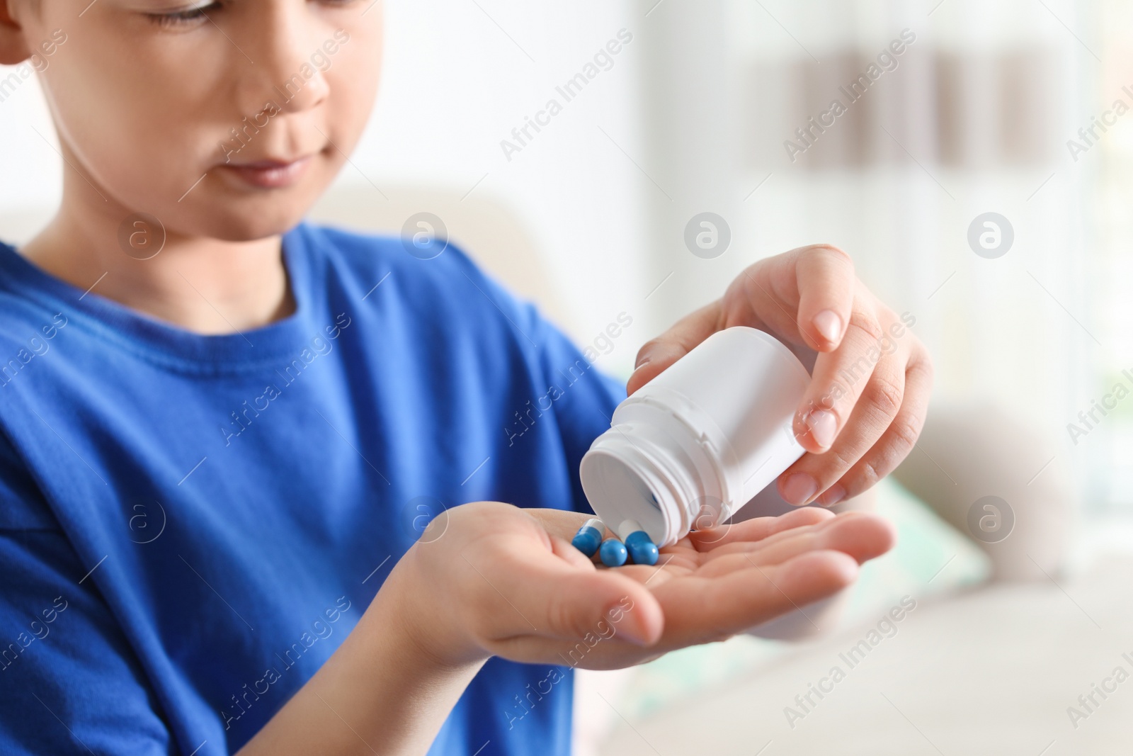 Photo of Little child with pills at home, closeup. Danger of medicament intoxication