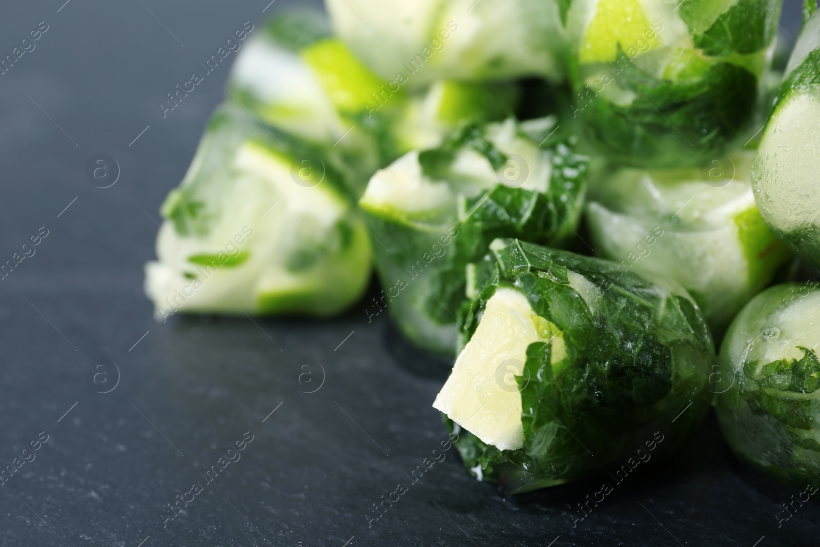 Photo of Lime and mint ice cubes on dark background, closeup