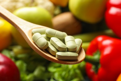 Photo of Dietary supplements. Spoon with pills over food products, closeup