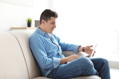Photo of Portrait of man with laptop on sofa, indoors