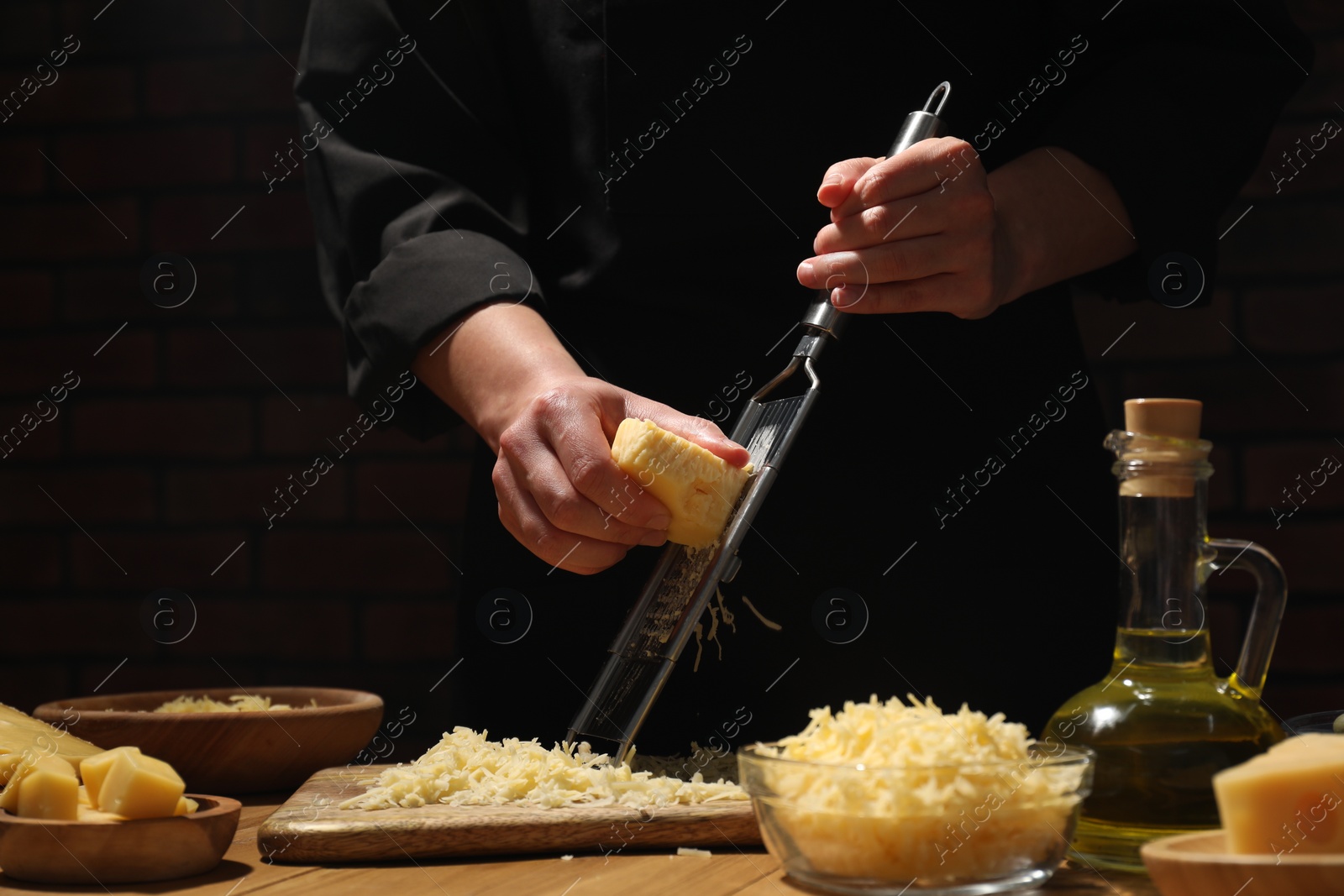 Photo of Woman grating cheese at wooden table, closeup