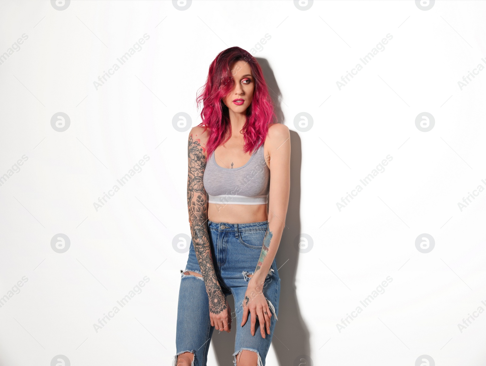 Photo of Beautiful woman with tattoos on body against light background