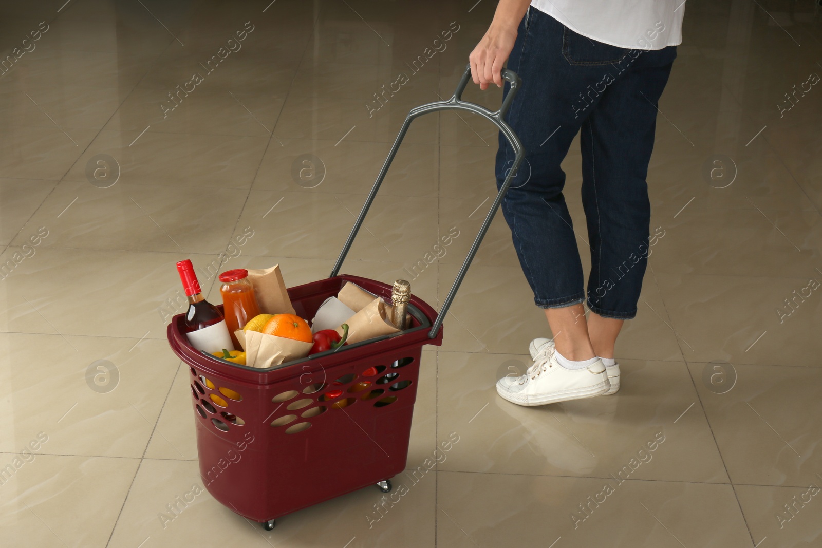 Photo of Woman with shopping basket full of different products, closeup
