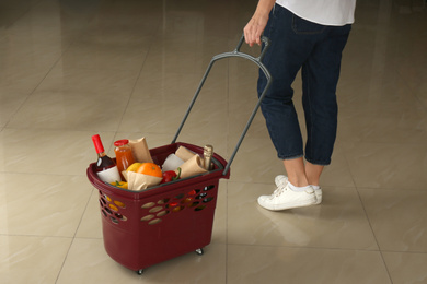 Photo of Woman with shopping basket full of different products, closeup