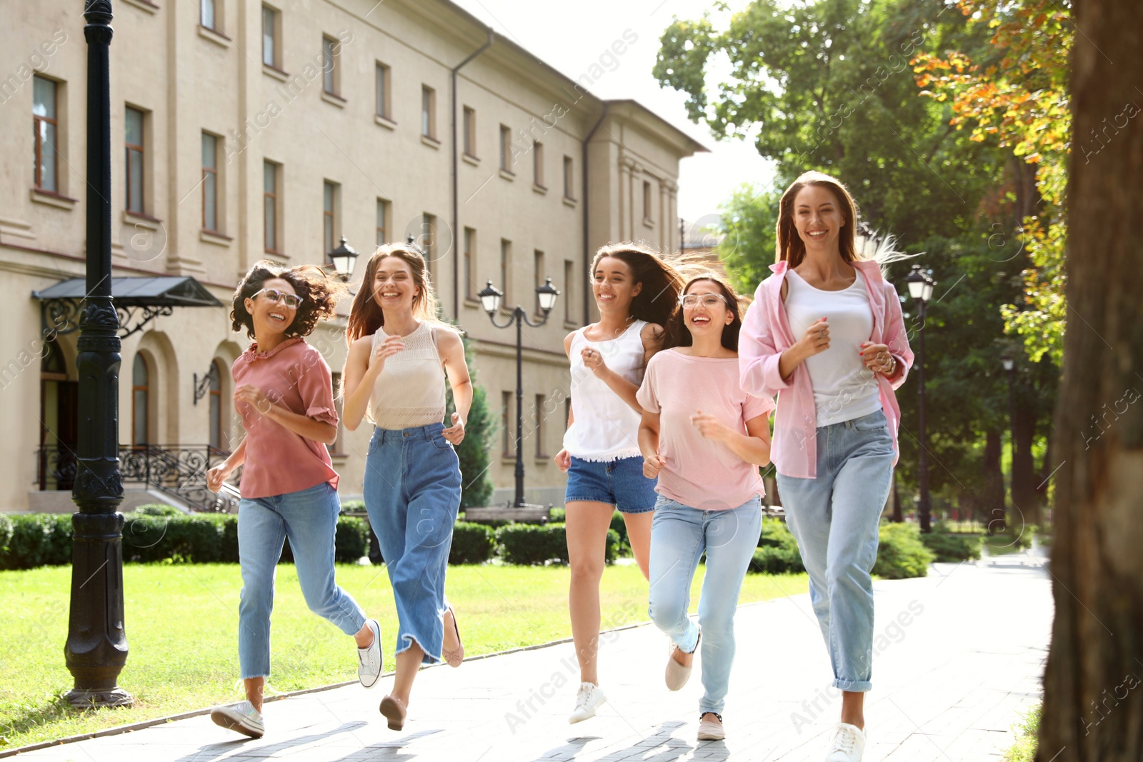 Photo of Happy women running outdoors on sunny day. Girl power concept