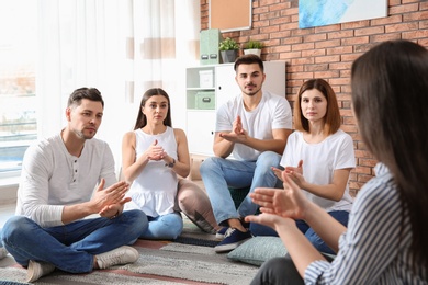 Photo of Group of young people learning sign language with teacher indoors