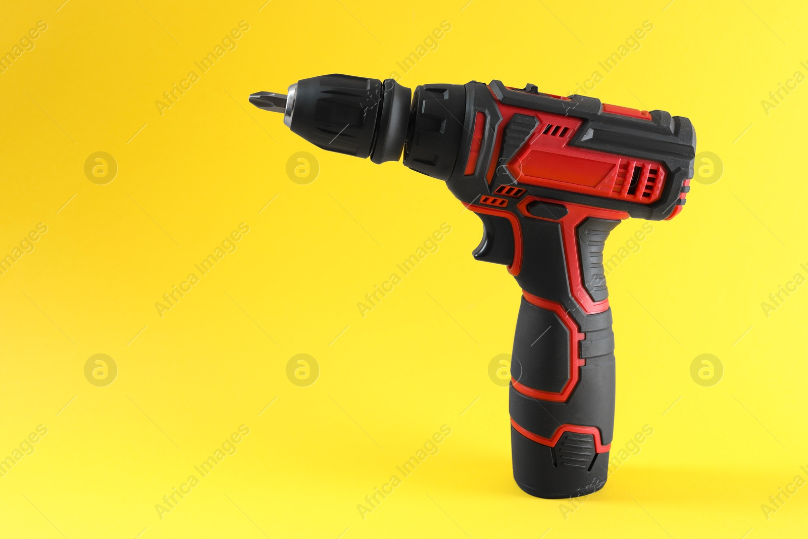 Photo of Modern electric screwdriver on yellow background. Space for text